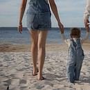 parents walking on the beach with their child. View from behind. Walking towards the water.