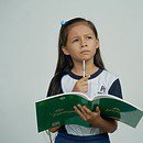 Girl with pencil in hand and green book open, making a choice.