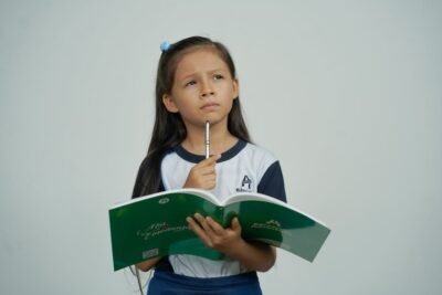 Girl with pencil in hand and green book open, making a choice.