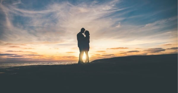 Man and woman embracing each other in front of a sunset.
