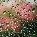Raindrops on glass with reflection of red and white lights