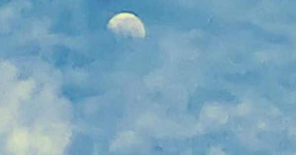 The image is of daytime waning moon, that is barely visible in a cloudy sky