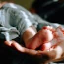 A baby's feet cradled in the palm of a hand