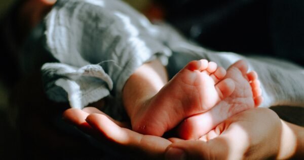 A baby's feet cradled in the palm of a hand