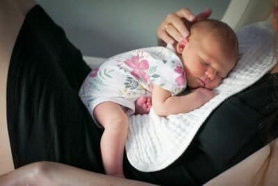 a woman holding a sleeping baby