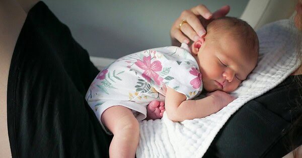 a woman holding a sleeping baby