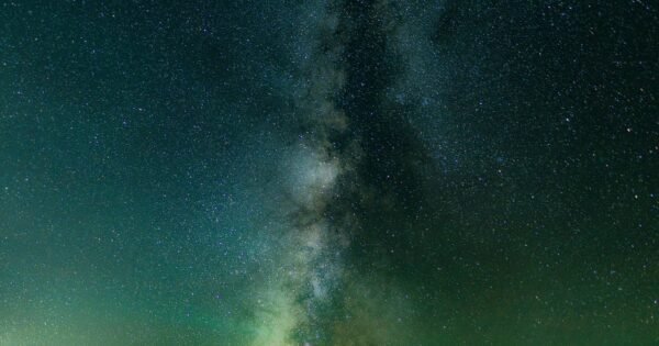 Stars along a dark sky nearby mountain peaks