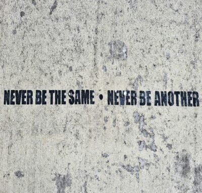 A gray and white background with black block letters reading Never be the same Never be Another