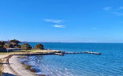 The image is of a picturesque blue bay with a pier or causeway