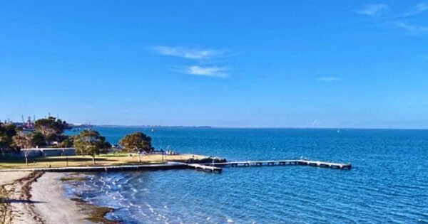The image is of a picturesque blue bay with a pier or causeway