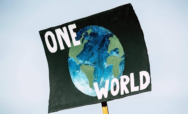 There is a blue background shown behind a sign with a painting of earth on it. There are also the words "One World" written on the sign for people to see