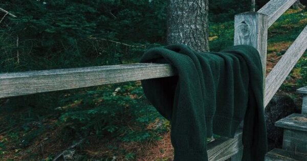 discarded sweater draped over a fence