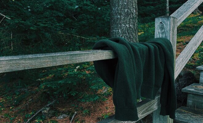 discarded sweater draped over a fence