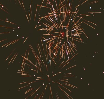 A black sky light up by streaks of red fireworks.