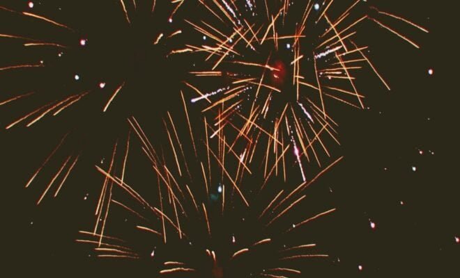 A black sky light up by streaks of red fireworks.