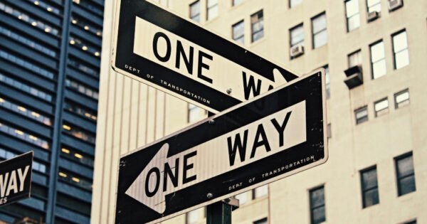 Two one way street signs pointing in opposite directions.