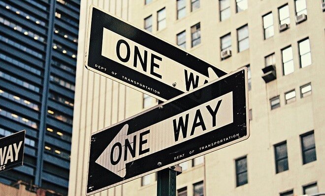 Two one way street signs pointing in opposite directions.