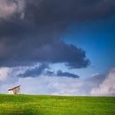 A lone house among an open field and a cloud covered sky