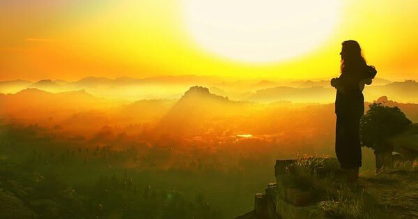 silhouette of woman overlooking mountain ranges at sunset