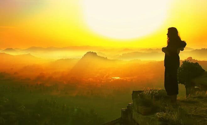 silhouette of woman overlooking mountain ranges at sunset