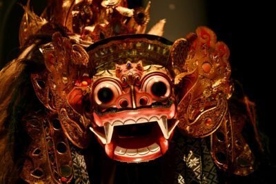 A red and gold dragon mask with open mouth and black eyes.