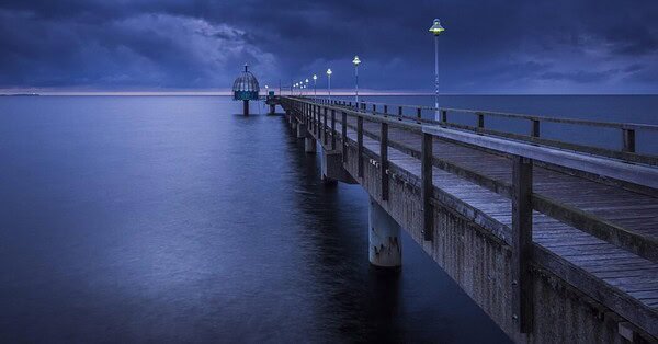 A dimly lit pier, made of grimy wood.