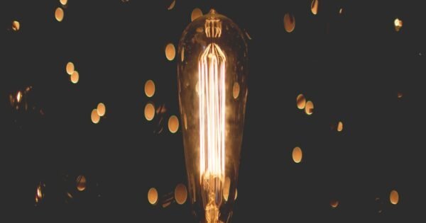 Black background with flickers of fluorescent light surrounding a fluorescent light bulb.