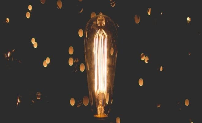 Black background with flickers of fluorescent light surrounding a fluorescent light bulb.