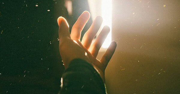 A hand, reaching for the sunlight streaming in from the curtains