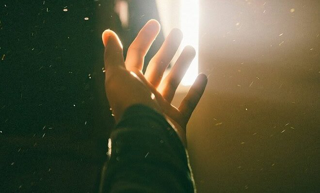 A hand, reaching for the sunlight streaming in from the curtains