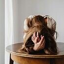 A woman leaning over a wooden table in frustration