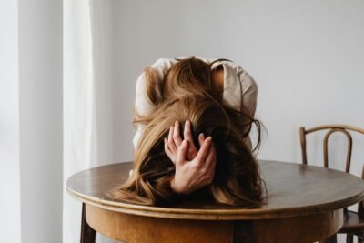 A woman leaning over a wooden table in frustration