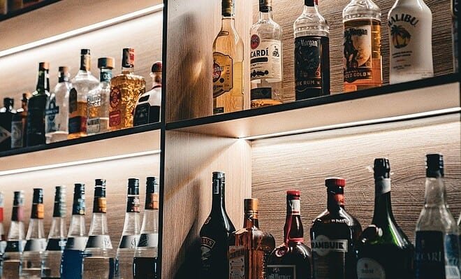Bottles of liquor sit in perfect rows along backlit shelves