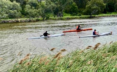 The image is of three kayakers paddling along a river
