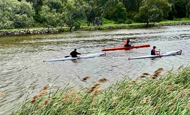 The image is of three kayakers paddling along a river