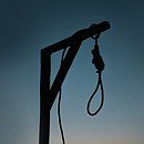 silhouette of a lone gallows and noose at sunset