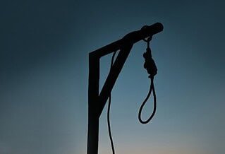 silhouette of a lone gallows and noose at sunset