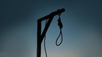 silhouette of a lone gallows and noose at sunset