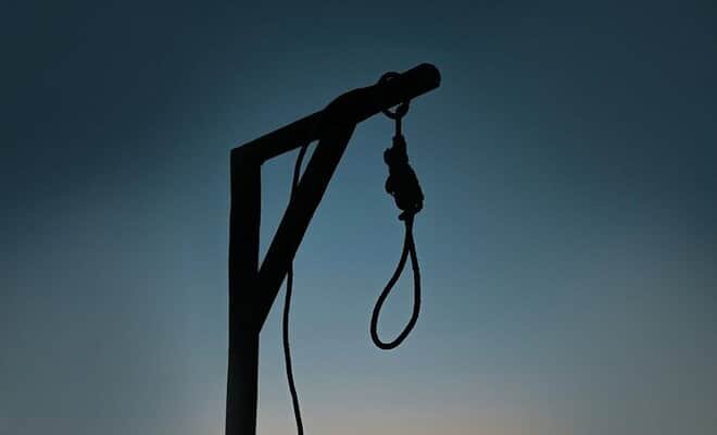 silhouette of a lone gallows and noose at sunset