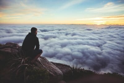 a man staring down from a mountain covered in the clouds