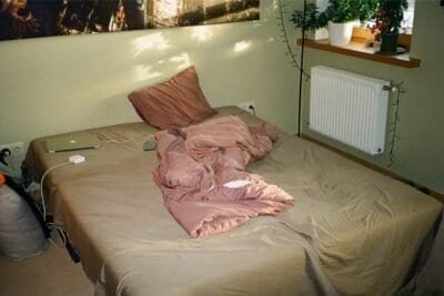 An unmade brown and pink bed.