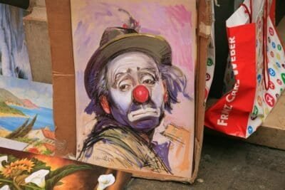 A painting of a sad man in clown makeup