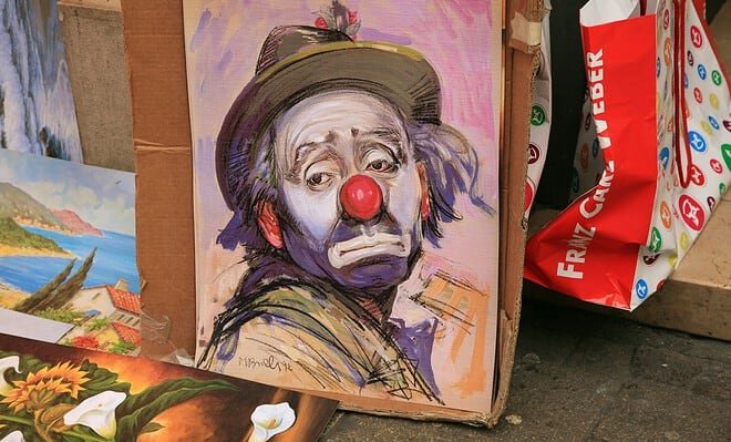 A painting of a sad man in clown makeup