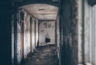 a decrepit hallway with debris in the floor