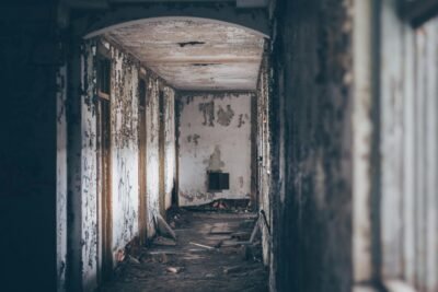 a decrepit hallway with debris in the floor