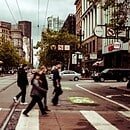 people walking across a crosswalk on a city street.