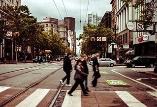 people walking across a crosswalk on a city street.