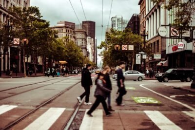 people walking across a crosswalk on a city street.