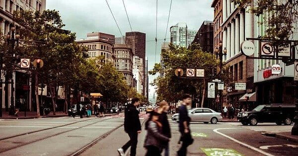 people walking across a crosswalk on a city street.