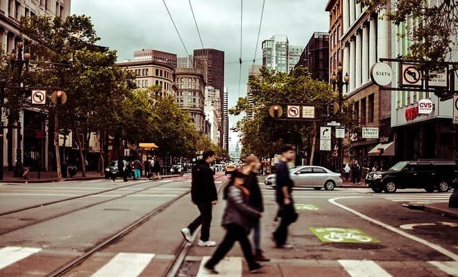 people walking across a crosswalk on a city street.